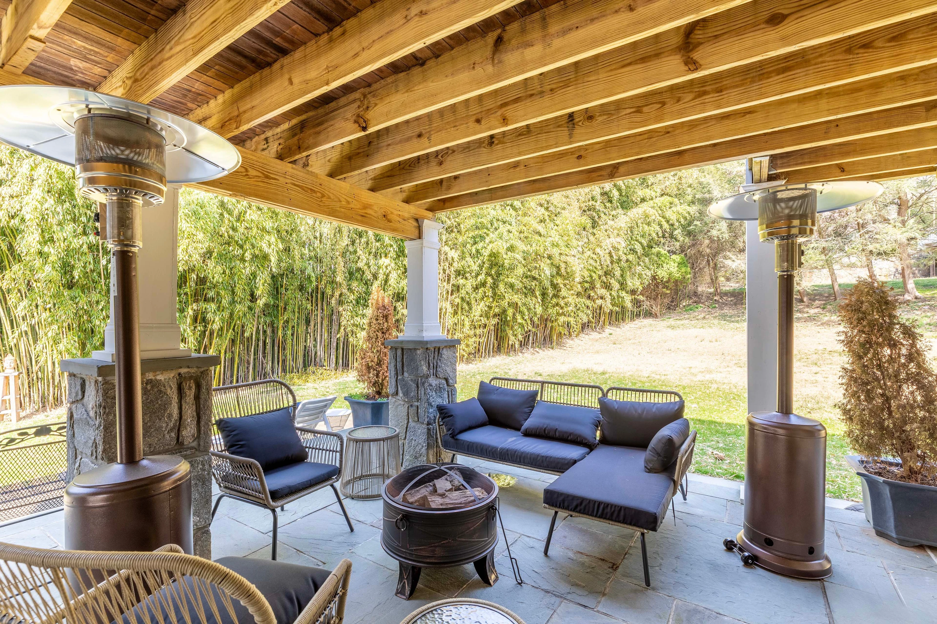 Stone Manor’s covered stone patio with lounge seating and a fire pit